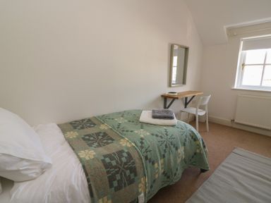 A bedroom with a bed a chair a wall mirror and a window at Craigluscar in Newport Pembrokeshire