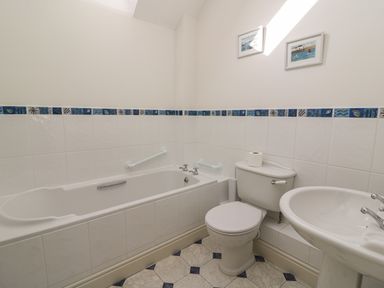 A bathroom with a bathtub toilet and sink with blue patterned tile trim at Craigluscar in Newport Pembrokeshire