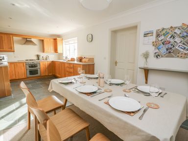 A kitchen with wooden cabinets and a dining table set for six at Craigluscar in Newport Pembrokeshire