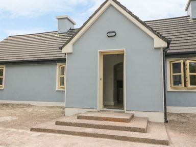Exterior view of a blue house with a small porch and steps leading to an open door at Dromstabla in Glencar
