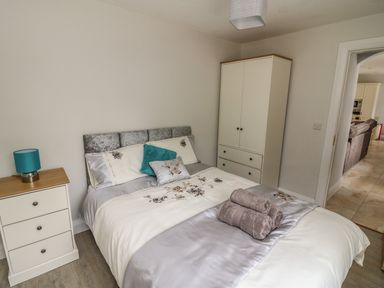 A bedroom with a bed with folded towels a three drawer chest and a wardrobe at Dromstabla in Glencar