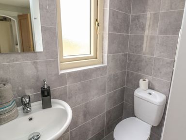 A bathroom with a toilet a sink with soap dispenser and towel and a window above the sink at Dromstabla in Glencar
