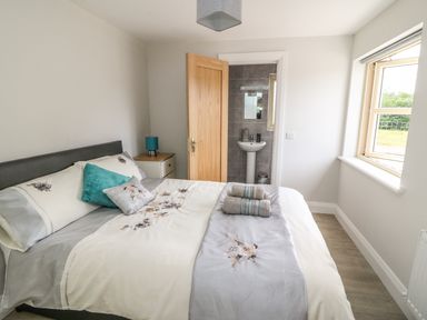 A bedroom with a bed towels on it and an open door leading to a bathroom with a sink at Dromstabla in Glencar