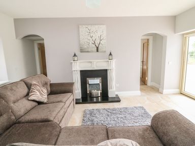 A living room with brown sofas a fireplace and a rug at Dromstabla in Glencar