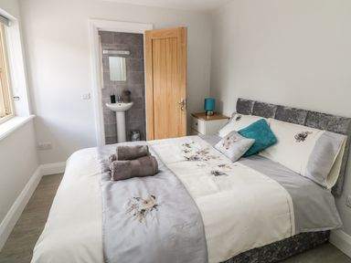 A bedroom with a bed and towels near an open door showing a sink at Dromstabla in Glencar
