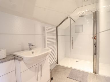 A bathroom with a sink cabinet towel rail and a glass enclosed shower at Llety Dewi in Lake Vyrnwy