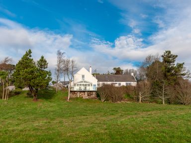 A white house with a glass porch surrounded by trees and grass at The Schooner in Goleen County Cork
