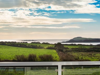A view of green fields and the ocean with islands in the distance at The Schooner in Goleen County Cork