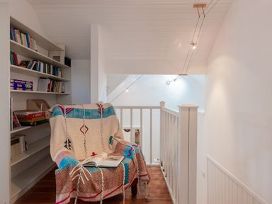 A reading nook with a chair covered in a patterned throw and an open book next to a bookshelf at The Schooner in Goleen County Cork