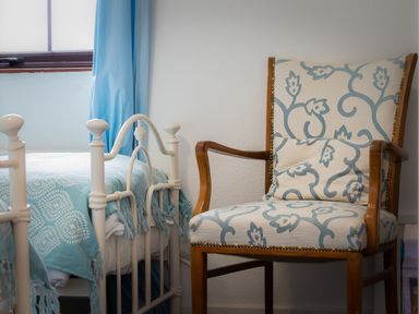 A bedroom with a white metal bed and a patterned armchair at The Schooner in Goleen County Cork