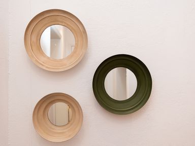 Three round mirrors with wide frames in beige and green colors mounted on a white wall at The Schooner in Goleen County Cork