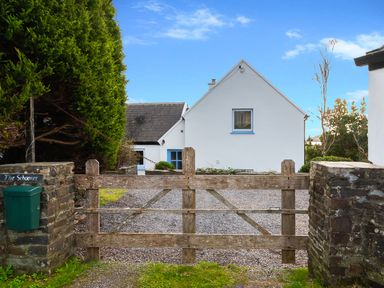 A gravel driveway with a wooden gate leading to a white house at The Schooner in Goleen County Cork