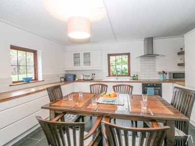 A kitchen with wooden dining table and chairs and kitchen cabinets with appliances at The Schooner in Goleen County Cork