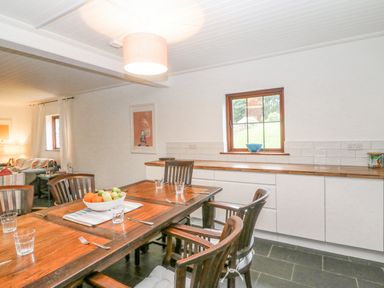 A dining area with a wooden table set with glasses and cutlery and white cabinets under a window at The Schooner in Goleen County Cork