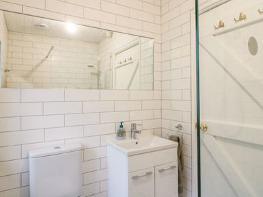A bathroom with a toilet a sink with cabinet and a mirror above at The Schooner in Goleen County Cork