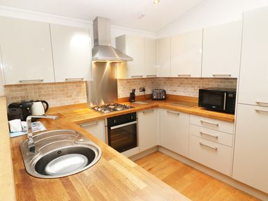 A kitchen with wooden countertops stove oven microwave and a sink at 6 Streamside Lanreath