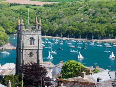 A church tower overlooking boats in a body of water at 6 Streamside in Lanreath