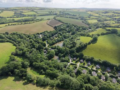 An aerial view of fields, trees, water, and houses at 6 Streamside in Lanreath