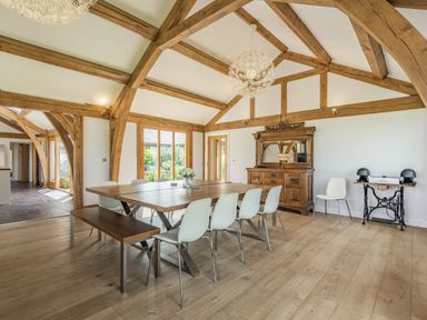 A dining room with wooden beams a table chairs a bench a cabinet and a side table with a stereo at Hen Hafod Talwrn near Llangefni