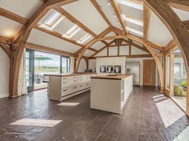 A kitchen with wooden beams skylights island units and glass doors at Hen Hafod Talwrn near Llangefni