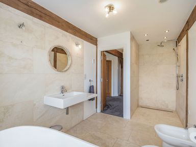A bathroom with a wall-mounted sink mirror and shower area at Hen Hafod in Talwrn near Llangefni