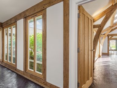 A hallway with wooden beams and windows alongside a wooden door at Hen Hafod in Talwrn near Llangefni