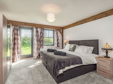 A bedroom with a double bed bedside table lamps curtains and a wardrobe at Hen Hafod in Talwrn near Llangefni