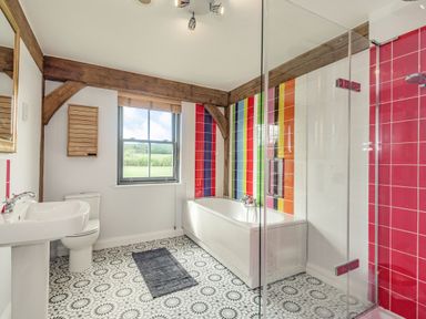 A bathroom with a bathtub shower toilet sink and patterned floor tiles at Hen Hafod in Talwrn near Llangefni