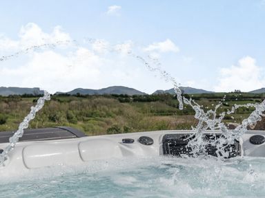 A hot tub with water jets and a countryside view at Hen Hafod in Talwrn near Llangefni
