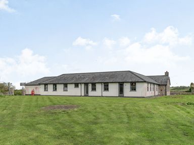 A single story house with multiple windows on a lawn at Hen Hafod in Talwrn near Llangefni