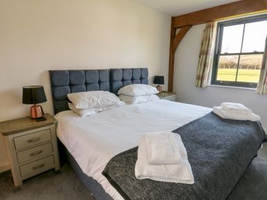 A bedroom with a double bed with white linens and towels on top and bedside tables with lamps at Hen Hafod in Talwrn near Llangefni
