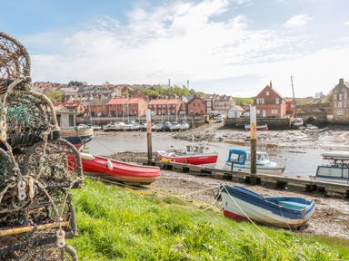 A small harbor with boats on the shore and dock with houses in the background at The Tannery in Whitby
