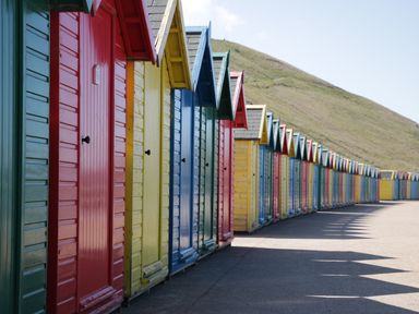 A row of colorful beach huts with peaked roofs along a paved walkway at The Tannery in Whitby