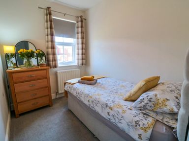 A bedroom with a single bed a wooden dresser with a mirror and a window with curtains at The Tannery in Whitby