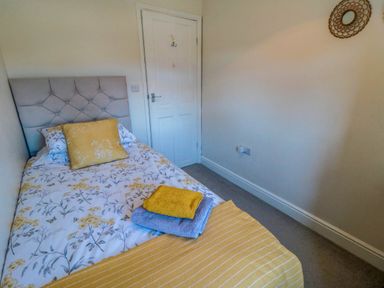 A bedroom with a single bed with floral bedding and folded towels on the bed at The Tannery Whitby