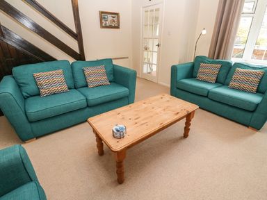 A living room with two teal sofas and a wooden coffee table at The Chace in Portreath