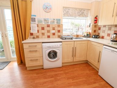 A kitchen with washing machine dishwasher sink countertop and cabinets at The Chace Portreath