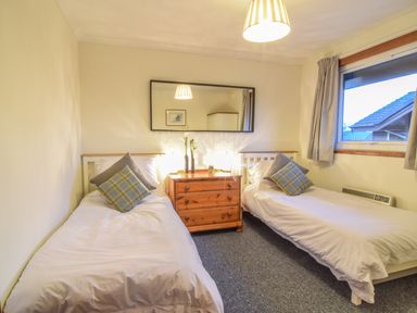 A bedroom with two single beds and a wooden dresser between them at Kestrel Lodge in Dumfries