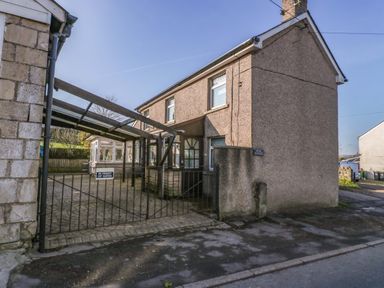 A two-story house with a gravel driveway and a black metal gate at Rose Cottage in Bream
