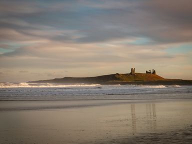 A coastal scene with waves and ruins on a distant hill at Oystercatcher in Embleton