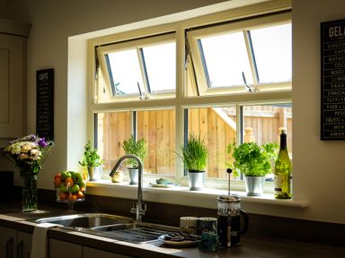 A kitchen sink with potted plants on the windowsill and a bowl of fruit on the counter at Oystercatcher in Embleton