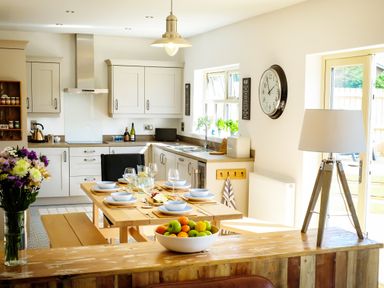 A kitchen and dining area with a set dining table and a bowl of fruit at Oystercatcher in Embleton