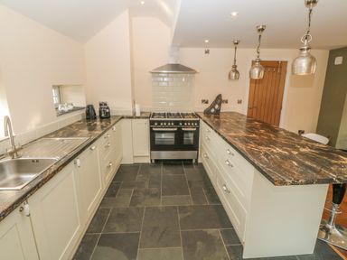 A kitchen with a central island counter and stove with oven at Rhos Y Foel Cottage in Nefyn