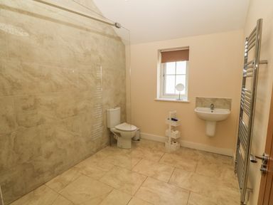 A bathroom with a toilet sink towel rack and window at Rhos Y Foel Cottage in Nefyn