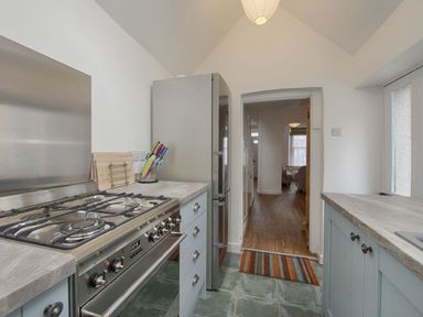 A kitchen with a gas stove fridge and countertops leading to a hallway at Anchorage in Watchet