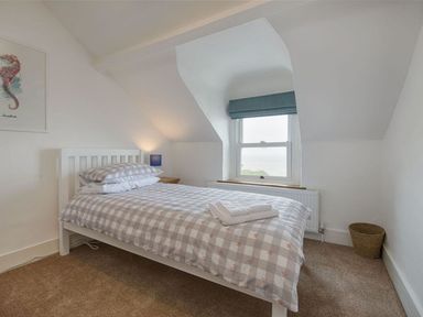 A bedroom with a bed near a window and a framed seahorse picture on the wall at Anchorage in Watchet