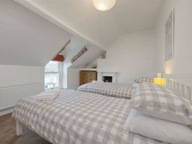A bedroom with twin beds and checked bedding next to a window with a chest of drawers at Anchorage in Watchet