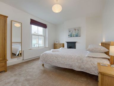 A bedroom with a bed a wardrobe a chest of drawers a mirror and a window at Anchorage in Watchet