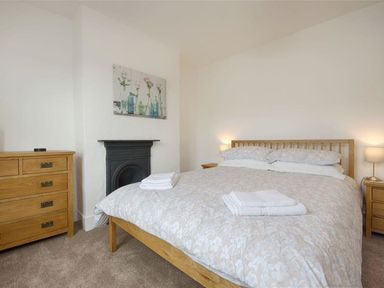A bedroom with a double bed with folded towels bedside tables with lamps and a wooden chest of drawers at Anchorage in Watchet