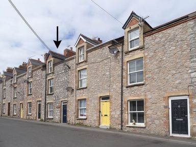 A row of stone terraced houses with various colored doors along a street with an arrow pointing to one house at Anchorage Watchet